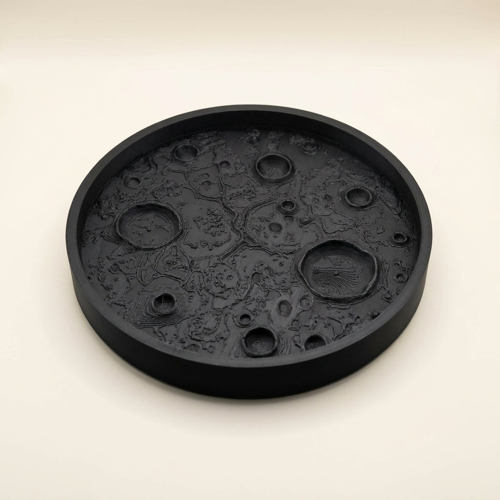 Matte black 3D printed moon tray with lunar surface texture holding small items