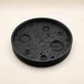 Matte black 3D printed moon tray with lunar surface texture holding small items