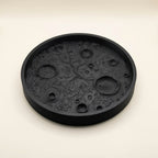 Matte black 3D printed moon tray with lunar surface texture holding small items